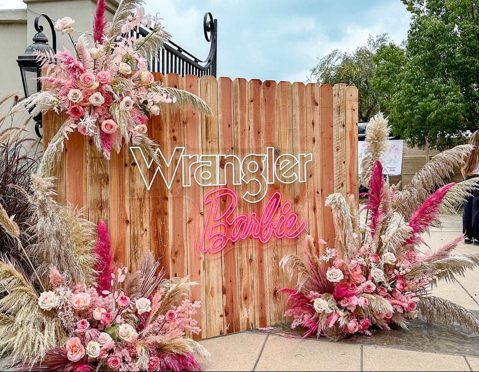 A Wrangler and Barbie brand activation: a neon sign framed with pink pampas and dried florals