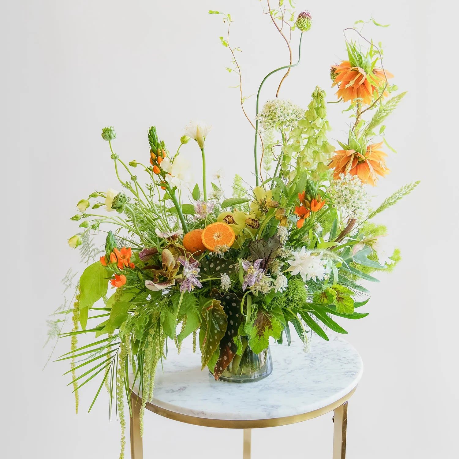 A sculptural orange and green arrangement on a marble side table